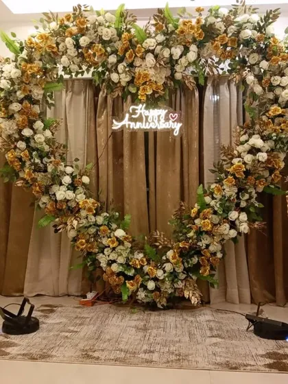 To celebrate a special anniversary, I created this grand heart-shaped arch completely covered in white and gold-toned flowers, with a custom neon sign and matching floral stands.