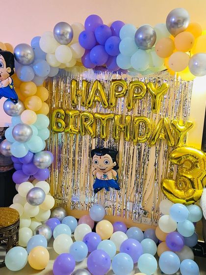 A close-up of the Chhota Bheem balloon arch and foil curtain backdrop.