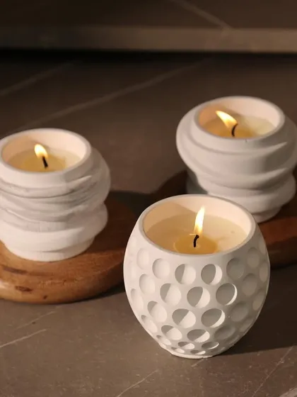 A trio of our minimal scented candles, featuring sculptural white jars with golf ball and swirl textures. They are perfect for creating a serene and stylish vignette on any surface.