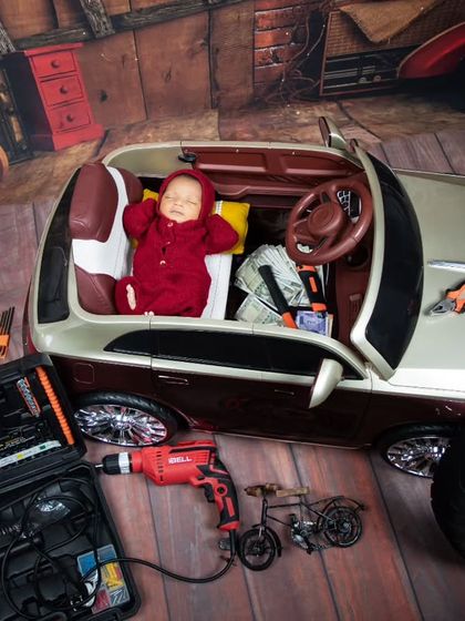 This little one is taking a nap after a hard day's work in the garage. The detailed setup with tools, a tire, and a toy car makes for a very convincing scene.