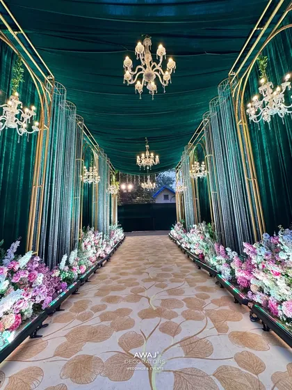 I design walkways that are an experience in themselves. Here, a path lined with lush florals and grand chandeliers guides guests through an emerald and gold archway, setting a tone of pure opulence.