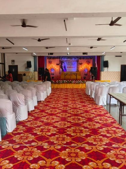 A full view of the hall for the event, showing the stage, aisle, and seating arrangement with white chair covers. I handle the complete setup from start to finish.