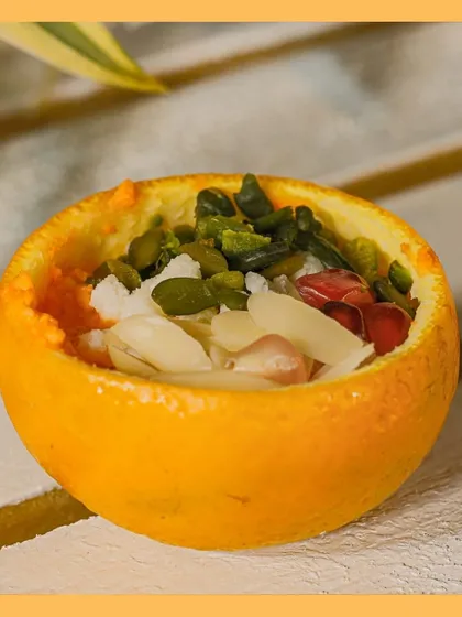 A close-up of our "Cosmic Dawn" dessert, showcasing the fresh ingredients and creative presentation inside a hollowed-out orange.