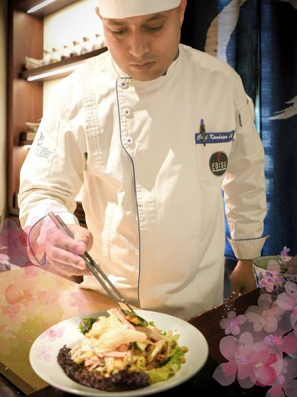 A chef carefully plates the Kani Salad, part of our Sakura menu. The artistic presentation is just as important to us as the flavor of the dish.