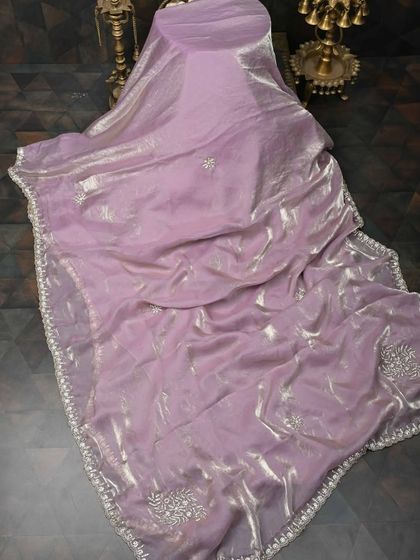A shimmering lavender saree in a lightweight, metallic fabric. The subtle sparkle and delicate embroidery make it a glamorous yet elegant choice for an evening event.