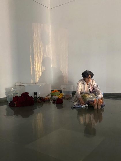 A still from Smitha Cariappa's performance, showing the artist's reflection in the gallery's polished floor, adding another layer to the visual experience.