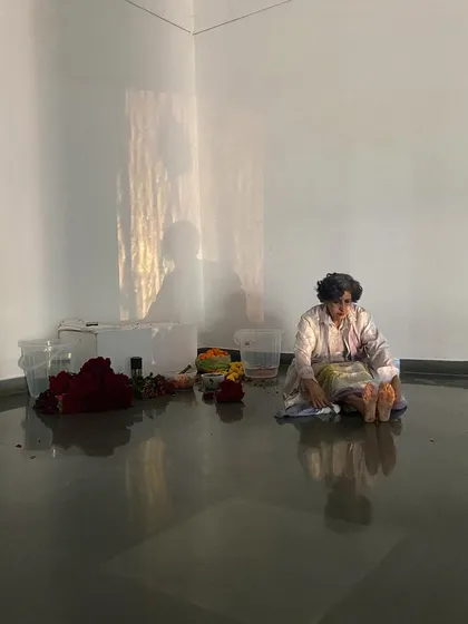 A still from Smitha Cariappa's performance, showing the artist's reflection in the gallery's polished floor, adding another layer to the visual experience.
