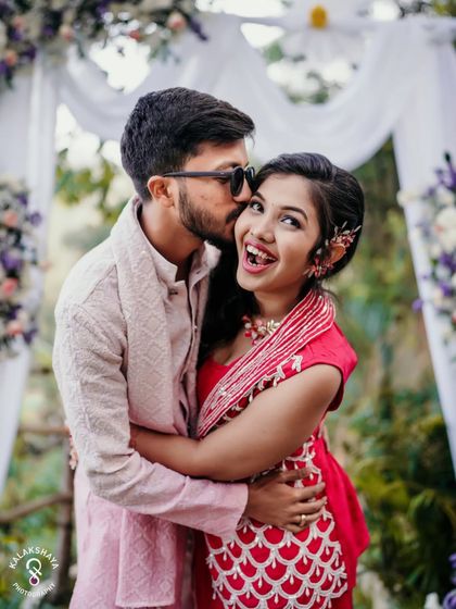 A sweet and candid moment with the groom kissing the bride's cheek during their Haldi celebration.