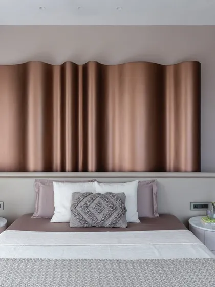 The master bedroom in 'The House of Arcs', where the fluid metallic headboard serves as the main focal point.