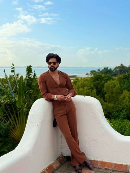 A relaxed pose against a stunning ocean backdrop, this image captures the essence of sophisticated resort wear.