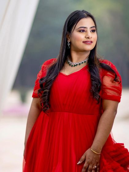 A smiling portrait of the bride-to-be in her red gown. The makeup is radiant and joyful, perfectly capturing her happiness.