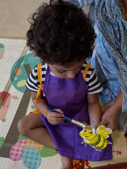 This little boy is concentrating hard on painting his bee. Wearing our colorful aprons is part of the fun, as we prepare to get messy and creative.