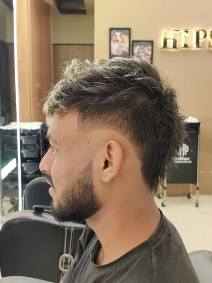 A modern men's hairstyle with a fade, textured top, and blonde highlights for a bold, edgy look.