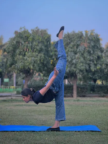 Practicing a standing split in the park. The fresh air and open space in Model Town add a special energy to our yoga sessions.