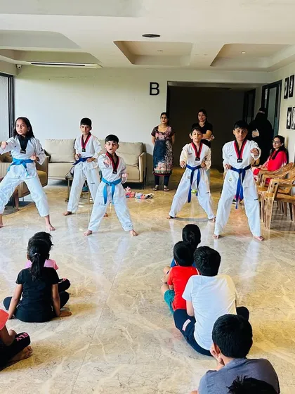 Blue belt students demonstrating their forms in front of an audience of younger kids and parents, inspiring the next generation.