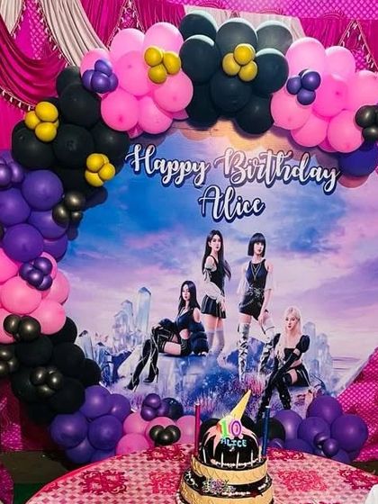 A Blackpink themed party setup with a custom circular backdrop and a balloon arch in the group's signature pink and black colors.