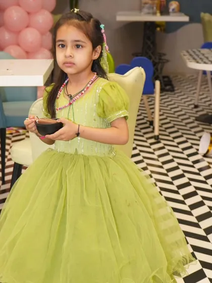 Giggles, glitter, and good vibes only! This birthday princess is enjoying a treat in our cafe, looking absolutely radiant in her beautiful green dress amidst the party fun.