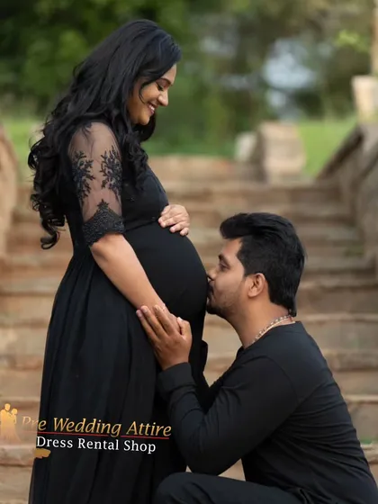 This classic black gown with delicate lace sleeves offers timeless elegance for your maternity shoot. It's a versatile choice that provides a sophisticated look, beautifully captured here in a tender moment between the expecting parents.