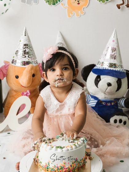 A sweet, frosting-covered face looks up at the camera during the jungle-themed cake smash.
