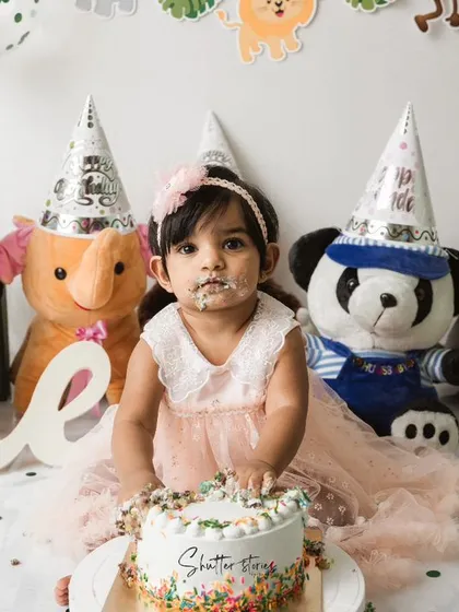 A sweet, frosting-covered face looks up at the camera during the jungle-themed cake smash.