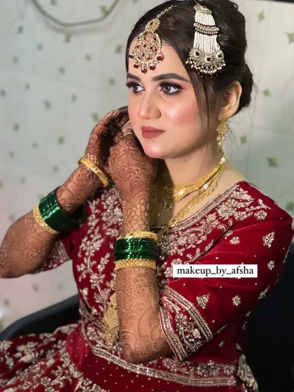 A candid moment as the bride adjusts her earring. This shot highlights the intricate jewellery and the beautiful henna design.