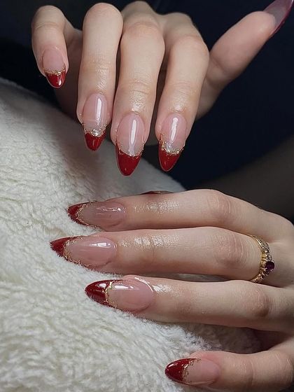 A dramatic red French tip with a glittery gold border. This is a glamorous and festive look, perfect for holidays or parties.
