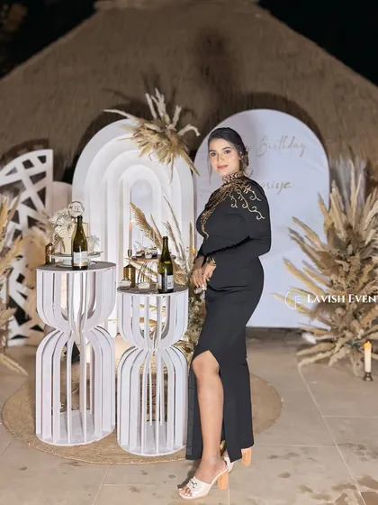 The birthday girl posing in front of her elegant boho-themed decor. The natural textures of the thatched roof and pampas grass complement her stylish look perfectly.