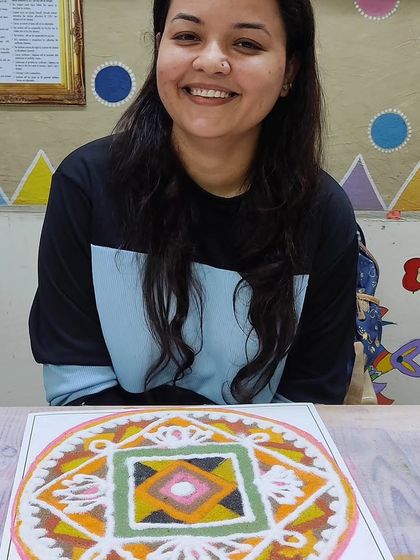 A smiling student with her geometric rangoli design. We love to see the diverse styles and creativity that emerge during our events.