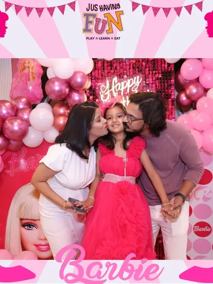 A picture of pure love and happiness. The birthday girl gets kisses from her parents in front of her fabulous Barbie-themed backdrop.