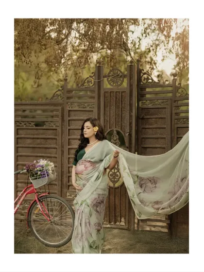 The flowing pallu of the saree catches the breeze, adding a sense of movement and life to this beautiful outdoor portrait. The rustic gate in the background adds to the old-world charm.