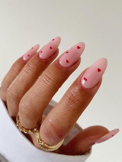A sweet and simple Valentine's Day nail idea. This soft pink manicure is adorned with tiny red hearts for a delicate and romantic touch.
