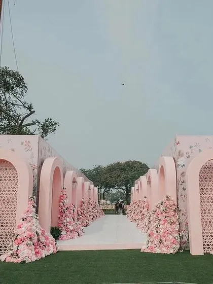 A wide view of the magnificent entrance for Yasha and Rahil's blush wedding. The series of pink arches and floral arrangements created a dramatic and immersive experience, leading guests to the seaside ceremony.