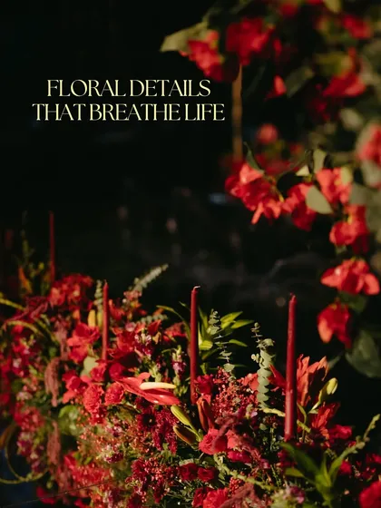 A close-up of the moody and romantic florals from the red Sangeet. The deep red flowers and taper candles create a sense of passion and drama, with the text "Floral Details That Breathe Life".