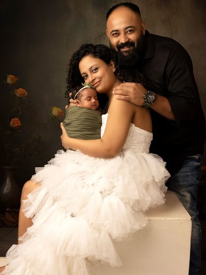 A full-length family portrait with their newborn. The composition creates a beautiful and balanced image, showcasing the new family of three.