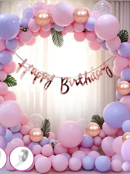 A beautiful balloon arch in pastel pink and purple with rose gold accents. This setup is perfect for birthdays and includes a "Happy Birthday" foil banner.