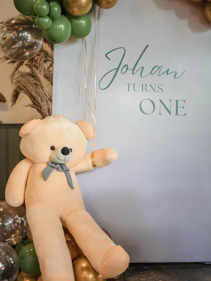 A simple, elegant backdrop for photos, featuring a large teddy bear and the birthday boy's name.