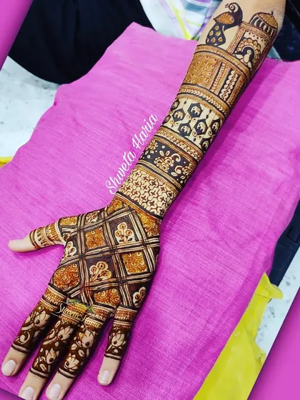 A traditional Rajasthani-style back-hand design. This pattern features a mix of checkwork, peacock motifs, and palace architecture, extending up the arm for a truly royal look.