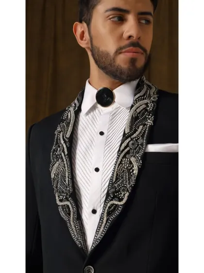 A detailed close-up of the Rud Avtar tuxedo's shawl collar. The meticulous embroidery in chrome silver and grey tones is reminiscent of nature's patterns, reimagined in metallic artistry.