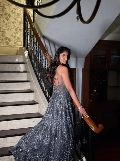 This full-length shot on the stairs shows how the makeup and outfit come together for a dramatic and elegant statement. The look is designed to be captivating from every angle.