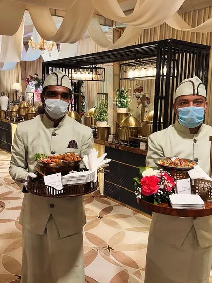 Our professional service team is the backbone of every flawless event. Dressed in sharp, elegant uniforms, they ensure every guest feels attended to, here seen serving appetizers before a grand wedding buffet.