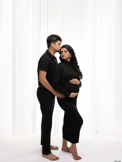A classic couple's portrait in matching black outfits. His kiss on her forehead is a timeless gesture of love and protection.