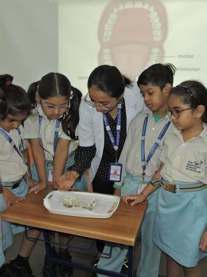 Students gather around a model of teeth to learn about dental anatomy. Our "Community Konnect" sessions on hygiene are interactive and highly informative.