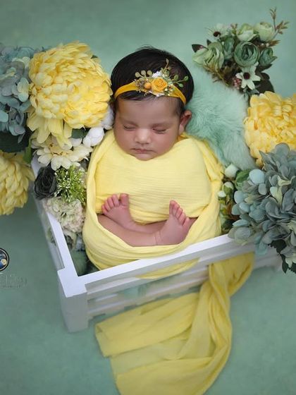 An overhead view of the newborn in the floral crate, showing the full arrangement and the baby's peaceful, sleeping state.