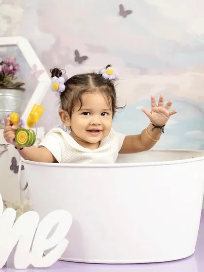 A wave to the camera from a cute white bucket. This first birthday shoot was full of playful props and happy moments.
