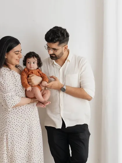 A classic family pose with a modern, minimalist feel. The parents' interaction with their baby makes this a warm and engaging portrait.