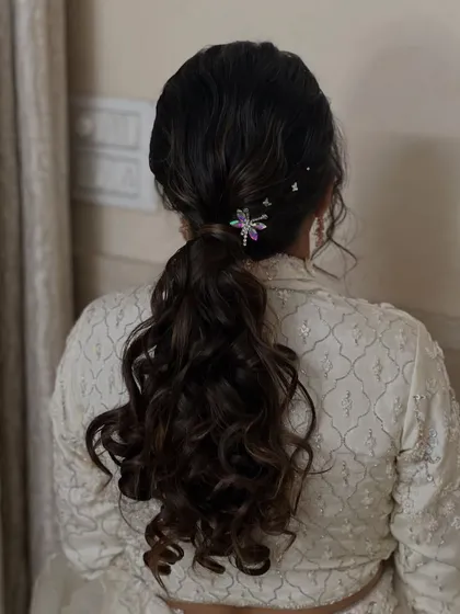 A modern and stylish ponytail with soft waves and a unique dragonfly accessory. This hairstyle is perfect for the bride who wants something a little different.