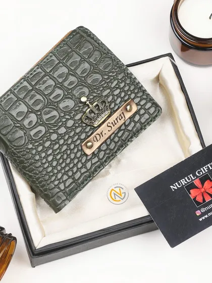 An olive green crocodile leather wallet personalized with a crown charm and a 'Dr.' title.