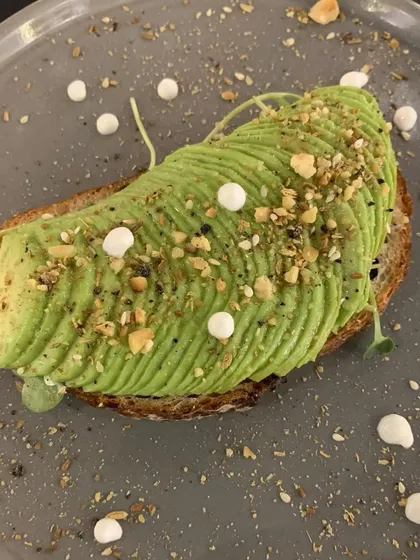A stunningly presented avocado toast, with perfectly fanned avocado slices and a sprinkle of nuts and seeds. A gourmet take on a breakfast classic.