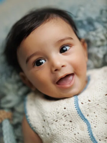 Those shiny eyes and that heart-melting smile say it all. Close-up portraits like this are essential in a baby milestone session to capture their developing personality.