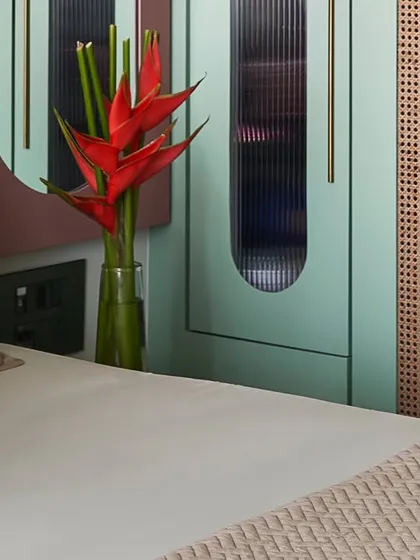 A detail of the master bedroom wardrobe, showing the interplay of mint green, cane, and fluted glass.